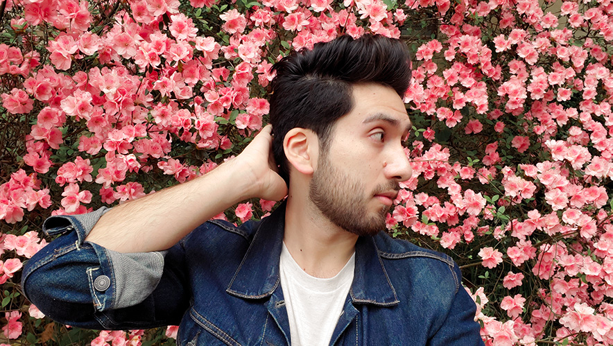 A rather cool guy in denim jacket standing in front of pink flowers.